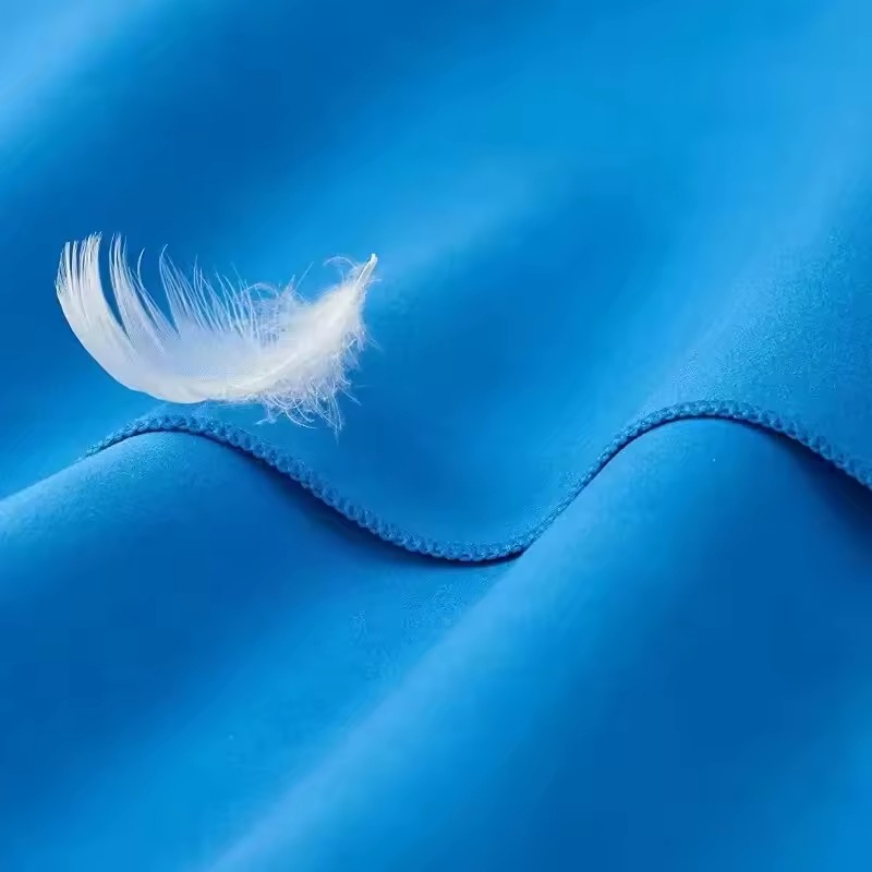 Soft microfiber towel fabric with a feather demonstrating softness
