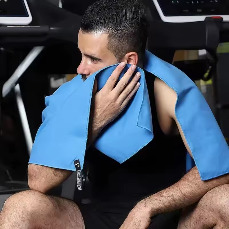 Person using a blue microfiber towel after exercise